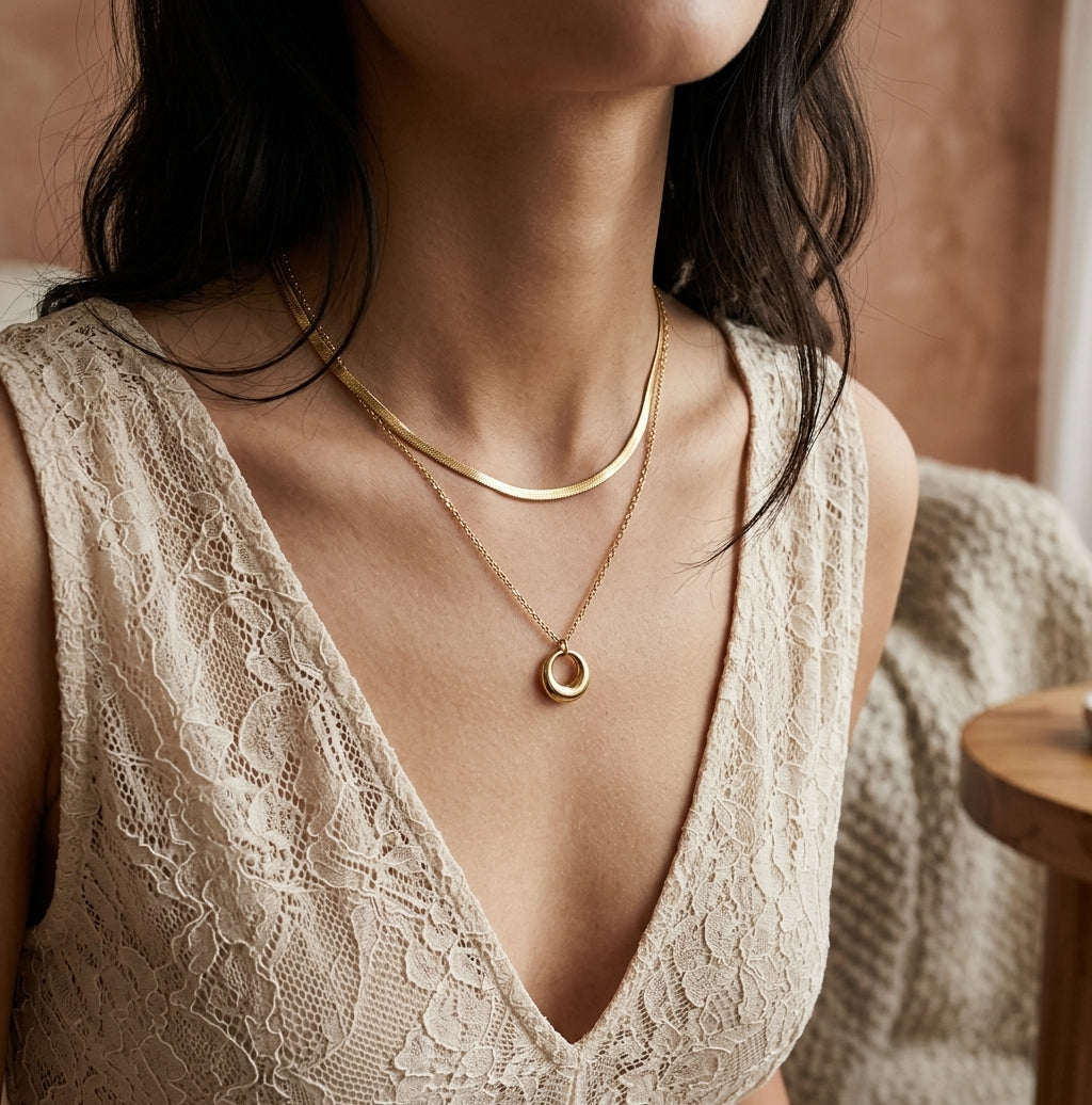 Duo de colliers dorés portés avec une maille écrue